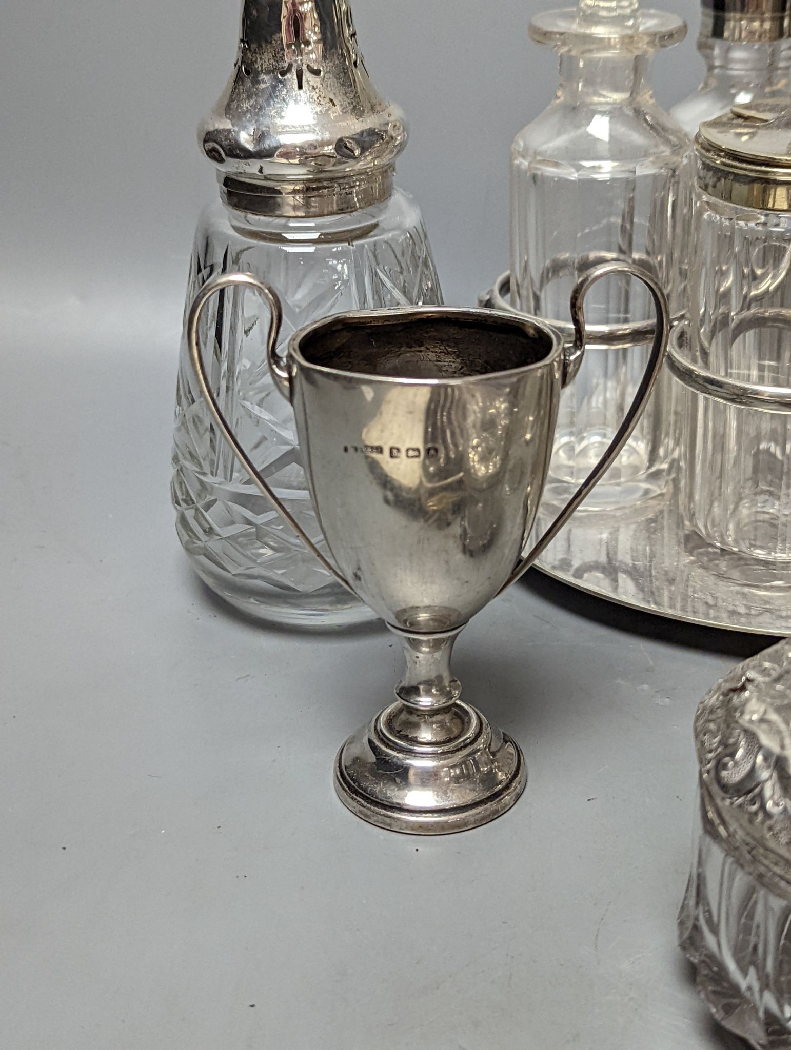 A plated cruet stand, two cased sets of silver handled tea knives, a silver domed ashtray(a.f.) silver trophy cup, four silver mounted glass jars and a plated napkin ring.